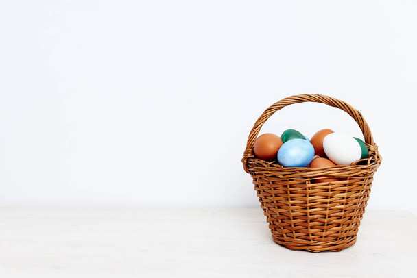 easter holiday with colored eggs in a basket light background  - Foto, Imagen
