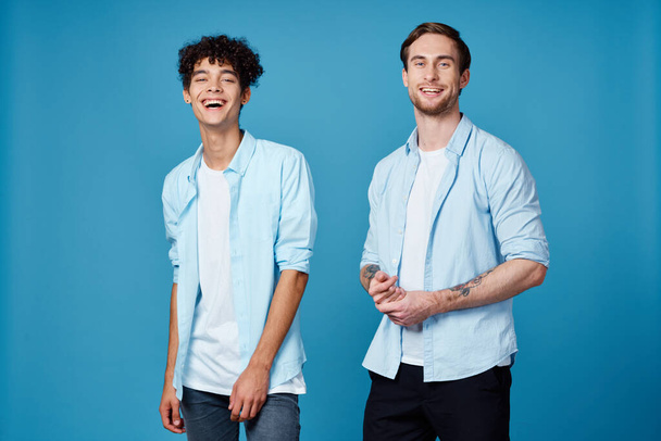 хлопці в однакових сорочках і футболка на синьому фоні друзі жестикулюють руками
 - Фото, зображення