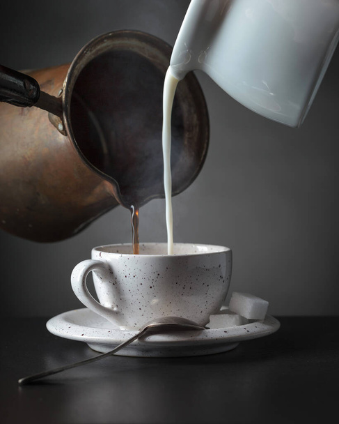 Cream and black coffee is poured into a cup. - Foto, Imagen