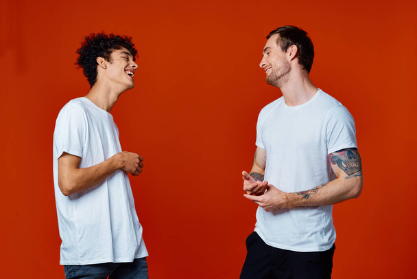 Dos amigos alegres en camisetas blancas comunicación aislado fondo divertido - Foto, Imagen