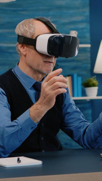Emekli adam sanal gerçekliği oturma odasında VR kulaklığı kullanarak yaşıyor. - Fotoğraf, Görsel