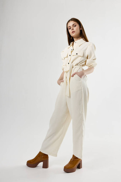 Woman in white jumpsuit with hands in pockets bottom view in full growth - Fotó, kép