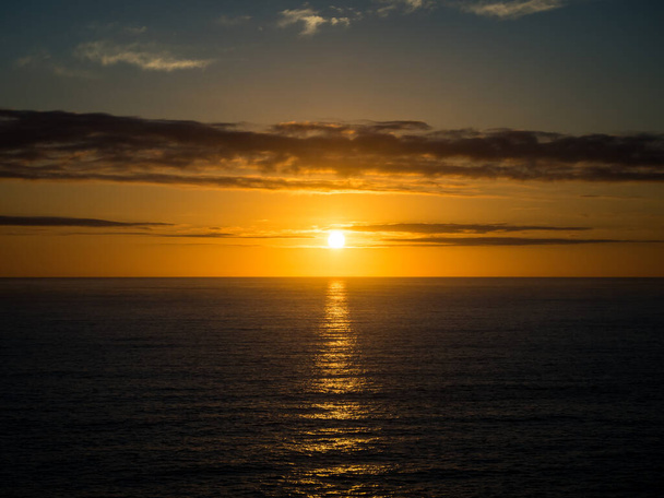 暖かい夏の夜の海の地平線の上に美しい黄金の夕日. - 写真・画像