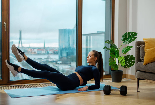 Femme mince pratique des exercices abdominaux sur tapis bleu - Photo, image