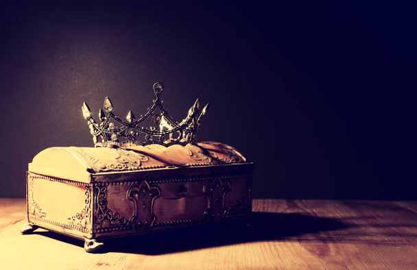low key image of beautiful queen or king crown over gold treasure chest. vintage filtered. fantasy medieval period - Φωτογραφία, εικόνα