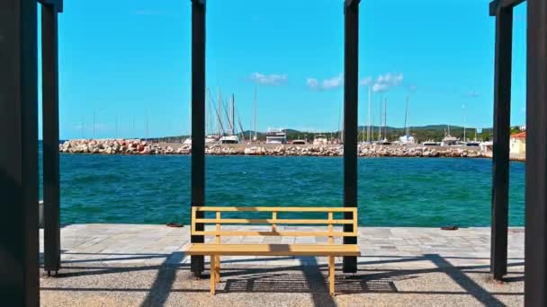 Vista del puerto marítimo con yates amarrados, mar Egeo, vista desde un mirador en un muelle con postes de metal negro y un banco en Nikiti, Grecia - Metraje, vídeo