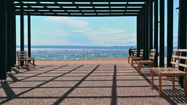 Un mirador en un muelle con postes de metal negro y bancos, mar Egeo en Nikiti, Grecia. Movimiento lento, alejando el efecto - Metraje, vídeo