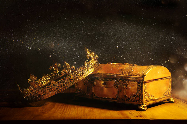 low key image of beautiful queen/king crown over gold treasure chest. vintage filtered. fantasy medieval period - 写真・画像
