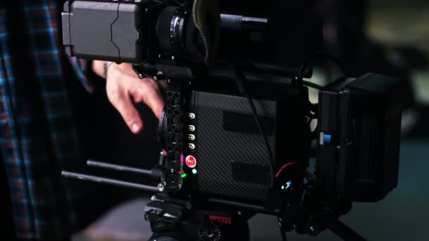 Hombre cambiando la lente en una cámara de vídeo profesional en el set de películas - Metraje, vídeo