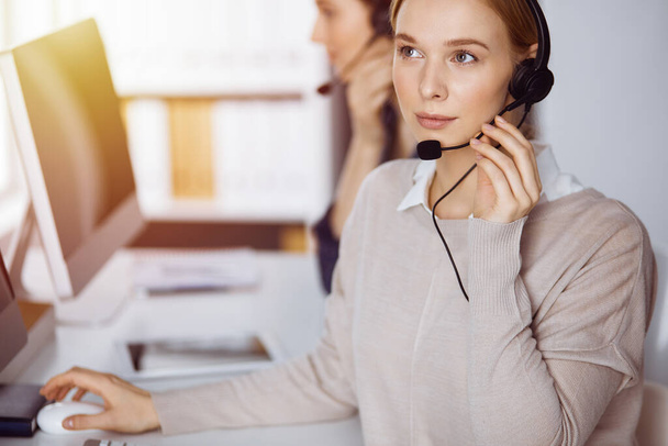 Businesswoman talking by headset in office. Call center and diverse people group in business - Fotografie, Obrázek