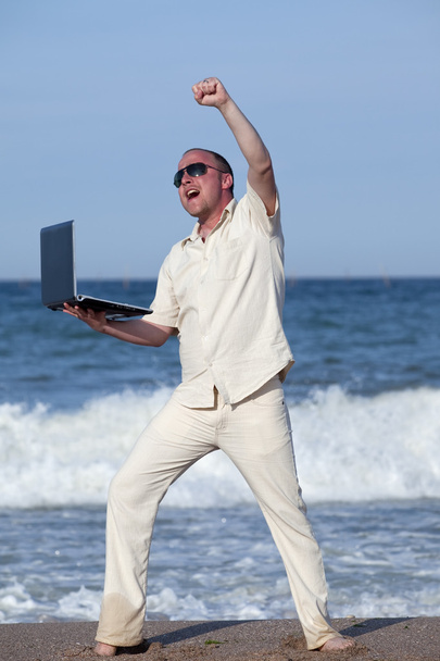 Young businessman at the beach with his laptop happy about success - Fotoğraf, Görsel