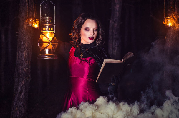 dívka sama v noci v lese vaří lektvar a zázraky pro manželství, obklopen svíčkami a kouřem - Fotografie, Obrázek