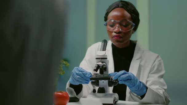 Πορτρέτο της φαρμακευτικής γυναίκας βάζοντας διαφάνεια κάτω από μικροσκόπιο - Πλάνα, βίντεο