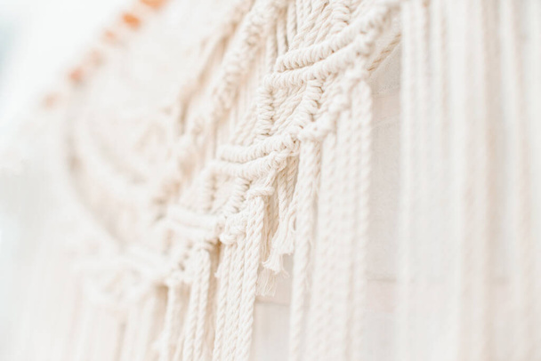 handmade macrame pattern a fragment of a wall panel in the boho style of beige cotton threads of natural color using the technique for home and wedding decor - Foto, imagen