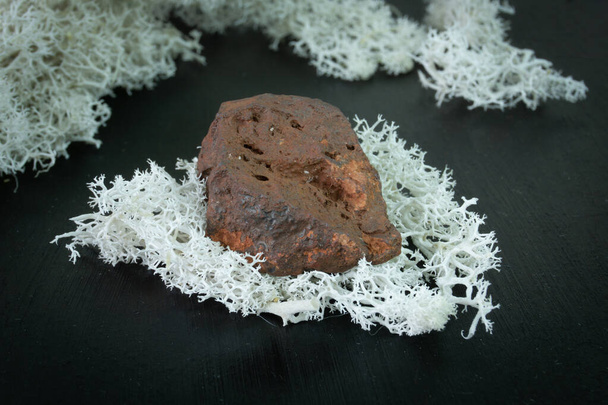 Goethit aus Marokko. Natürlicher Mineralstein auf schwarzem Grund, umgeben von Moos. Mineralogie, Geologie, Magie, Halbedelsteine und Mineralproben. Makroaufnahme aus nächster Nähe - Foto, Bild