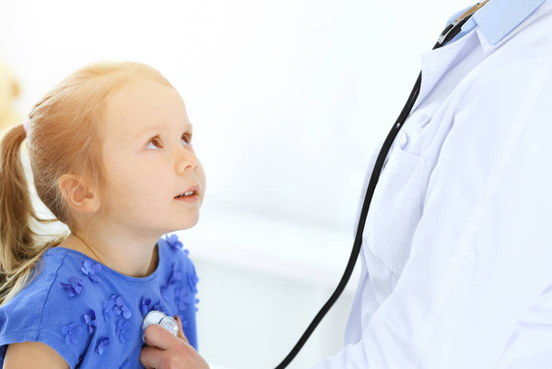 Doctor examining a little girl by stethoscope. Happy smiling child patient at usual medical inspection. Medicine and healthcare concepts - Photo, Image