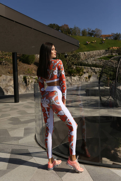 fashion outdoor photo of beautiful woman with dark hair in sportive suit posing in terrace - Fotografie, Obrázek