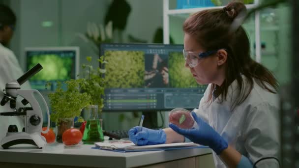Bióloga escribiendo experiencia médica mientras sostiene placa petri con carne de res vegana - Imágenes, Vídeo