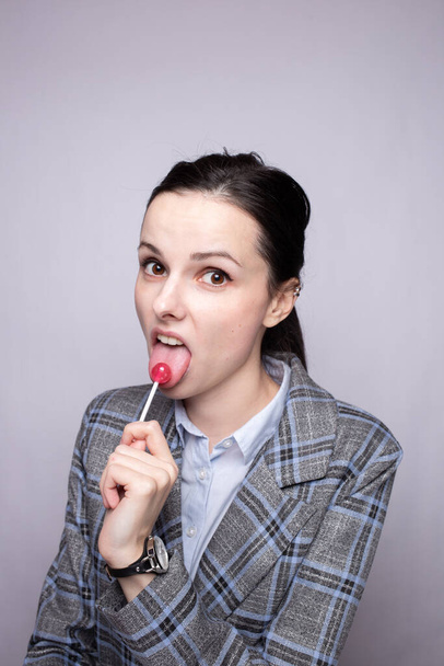 businesswoman eating lollipop, gray background - Valokuva, kuva
