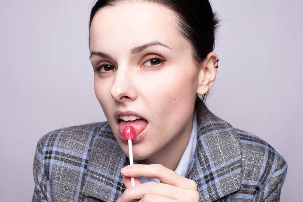 businesswoman eating lollipop, gray background - Photo, image