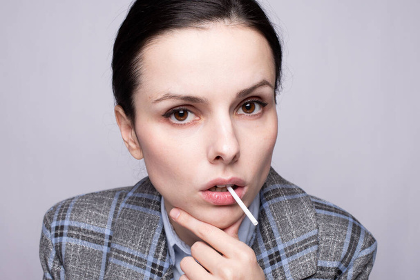 businesswoman eating lollipop, gray background - Photo, image