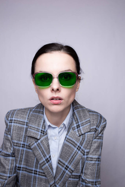 žena v zelených brýlích a šedém kostkovaném obleku - Fotografie, Obrázek