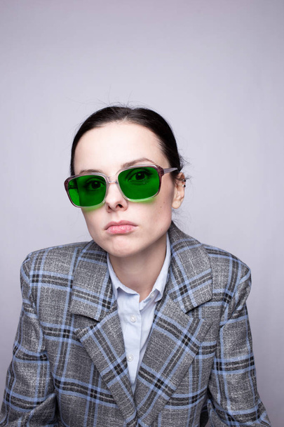 woman in green glasses and gray plaid suit - Фото, изображение