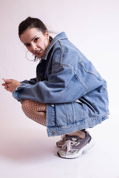 woman in denim jacket, shorts and sneakers, on white studio background - Foto, immagini