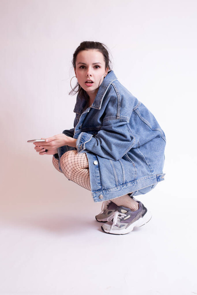 woman in denim jacket, shorts and sneakers, on white studio background - Foto, Imagem