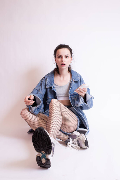 woman in denim jacket, shorts and sneakers, on white studio background - Foto, Imagen