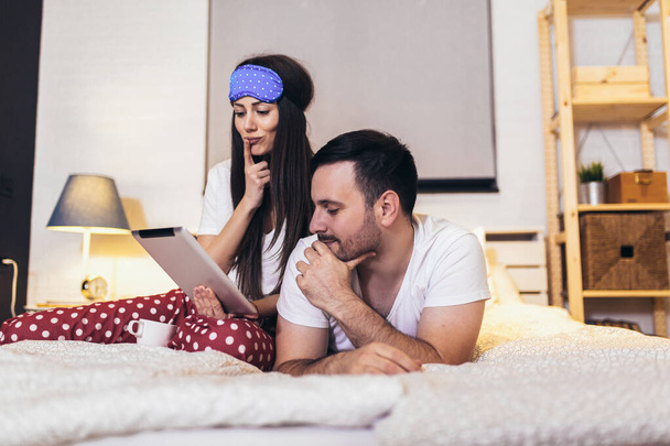 Sorrindo relaxado jovem casal usando tablet digital na cama em casa - Foto, Imagem