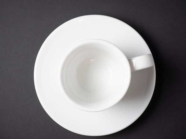 white coffee cup and saucer made of porcelain on a black background. Top view, flat lay - Photo, Image