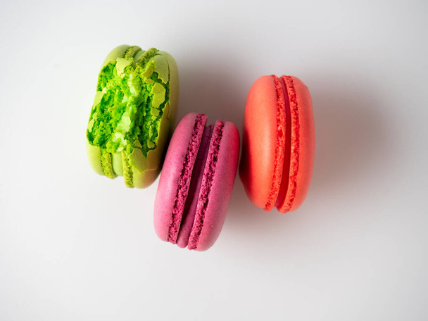 three macaroon cookies on a white background. One of them is bitten off. Top view, flat lay - Foto, Imagem