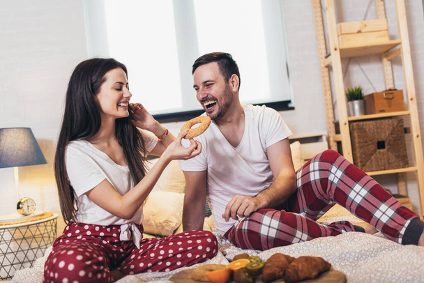 Cute couple having breakfast in bed in the bedroom - Photo, Image