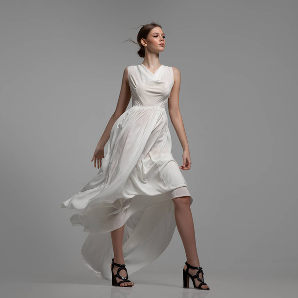 Donna di moda posa in abito bianco in piena crescita. Fondo grigio - Foto, immagini