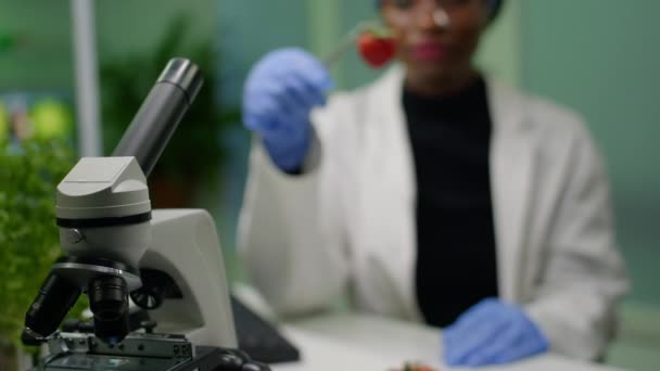Biólogo africano segurando morango injetado com líquido de dna com pinças médicas - Filmagem, Vídeo