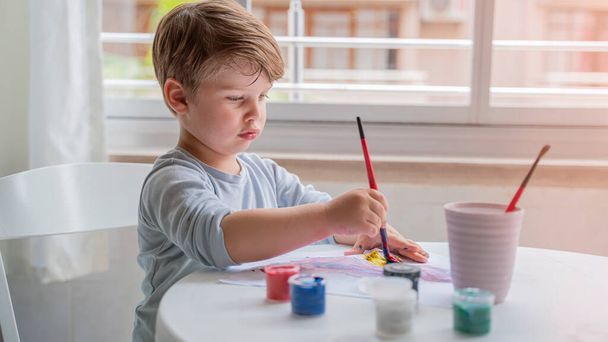 een kindje tekent met verf - Foto, afbeelding