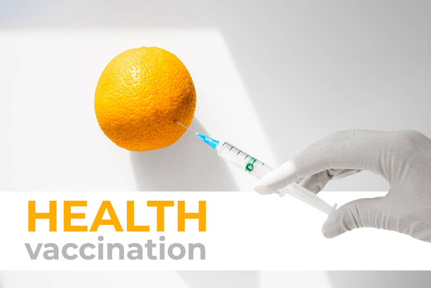Laborant mit Schutzhandschuhen spritzt eine Orange. Gentechnik. Spezialisten bekommen neue Obstsorten unter Laborbedingungen - Foto, Bild