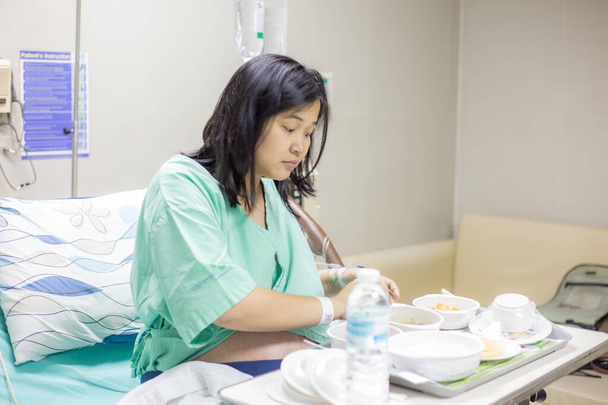 Mujer feliz paciente disfrutando de la comida en la cama de hospital, el paciente y el concepto de hospital - Foto, Imagen