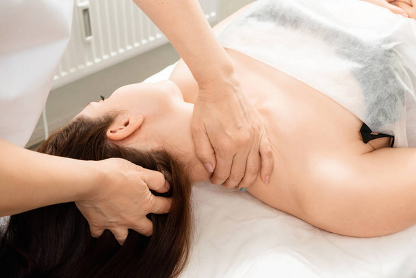 Uma linda garota está fazendo uma massagem no pescoço. Cuidados com a pele, esteticista, tratamentos de spa, relaxamento - Foto, Imagem
