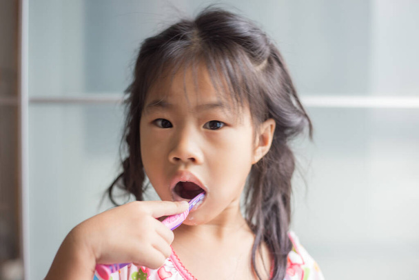 Pequeña chica asiática cepillándose los dientes en baño auto cepillarse los dientes - Foto, imagen