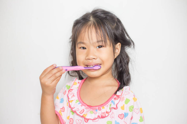 Kis ázsiai lány mossa a fogát a fürdőszobában önmosó fogak - Fotó, kép