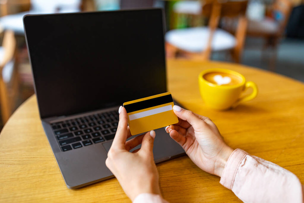 Интернет-шопинг в интернет-концепции. Женщина с помощью кредитной карты и ноутбука, сидя в кафе - Фото, изображение