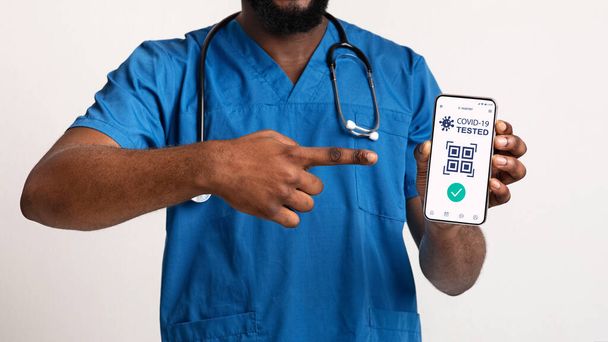 Чорний лікар показує мобільний телефон з цифровим е-паспортом для ковадла-19
 - Фото, зображення