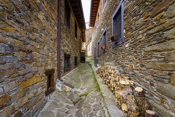 Smalle steeg tussen oude stenen huizen, een fiets en brandhout voor de winter. La Hiruela Madrid. Europa. - Foto, afbeelding
