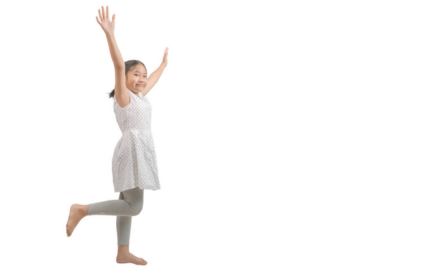 dítě dívka zvedne ruku a zvedne jednu nohu izolované na bílém pozadí., Happy a vítězný koncept - Fotografie, Obrázek