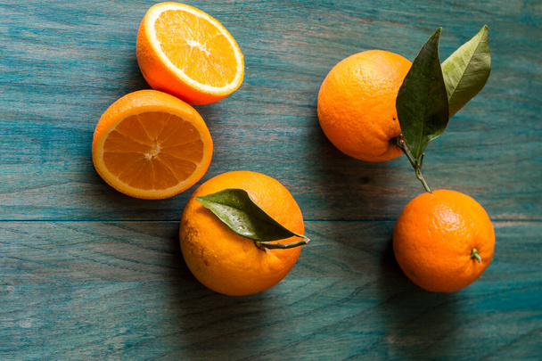 Orange cut in half and other oranges on ultramarine colored wooden background - Φωτογραφία, εικόνα