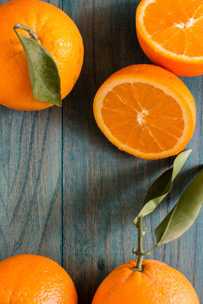 Πορτοκαλί κομμένο στη μέση και άλλα πορτοκάλια σε πολύ χρωματιστό ξύλινο φόντο - Φωτογραφία, εικόνα