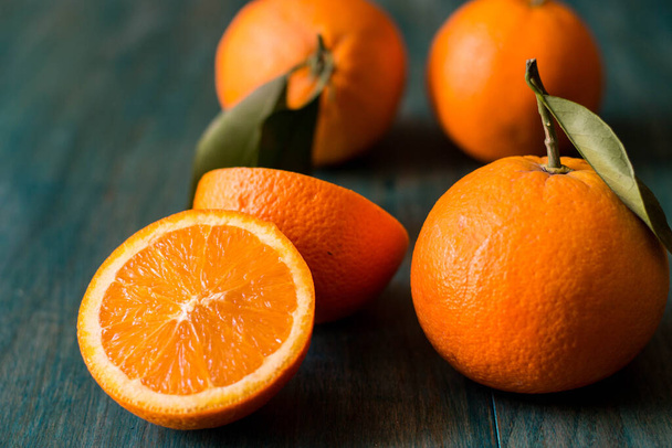 Pomarańczowy pokrojony na pół i inne pomarańcze na ultramorskim kolorowym drewnianym tle - Zdjęcie, obraz