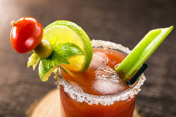 Canadian Caesar drink. Made with vodka, hot sauce and Worcestershire sauce, served with ice in a celery glass with a salted rim, decorated with a celery stalk and lemon slice. - Photo, Image